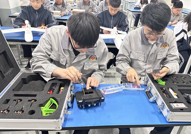 学生在实训车间专注操作设备，周围是现代化数控机床